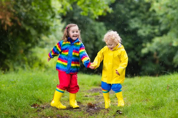 Crianças brincam na chuva e na poça no outono — Fotografia de Stock