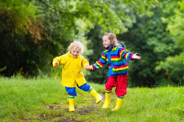 Crianças brincam na chuva e na poça no outono — Fotografia de Stock