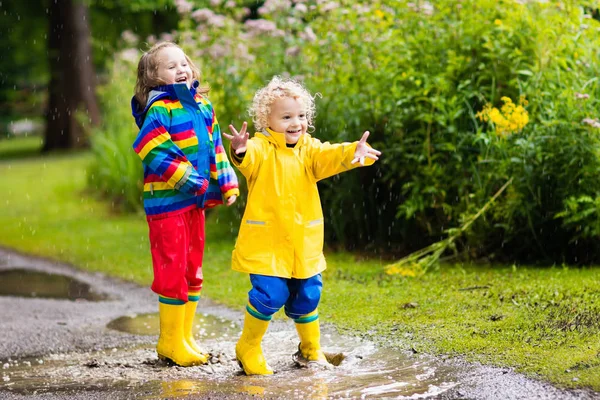I bambini giocano sotto la pioggia e la pozzanghera in autunno — Foto Stock