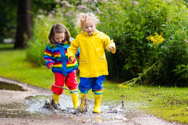 Los niños juegan bajo la lluvia y charco en otoño — Foto de Stock