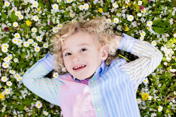 Bambino sul prato verde erba con fiori estivi — Foto Stock