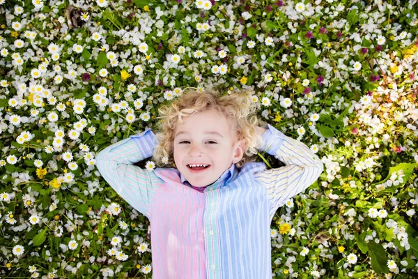 Niño en césped de hierba verde con flores de verano —  Fotos de Stock