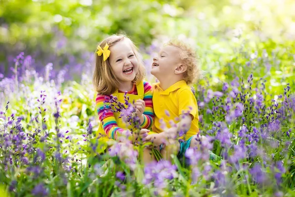 ブルーベルの花の咲く庭で遊ぶ子供たち — ストック写真