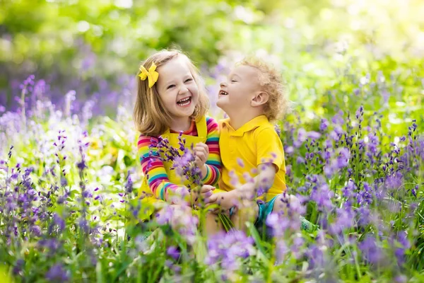 Kinderen spelen in de bloeiende tuin met bluebell bloemen — Stockfoto