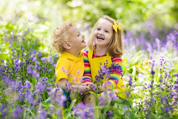 Дети играют в цветущем саду с цветами колокольчика — стоковое фото
