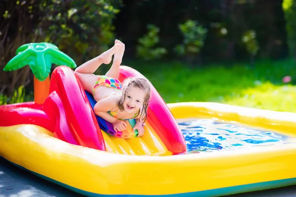 Menina que joga na piscina inflável do jardim — Fotografia de Stock