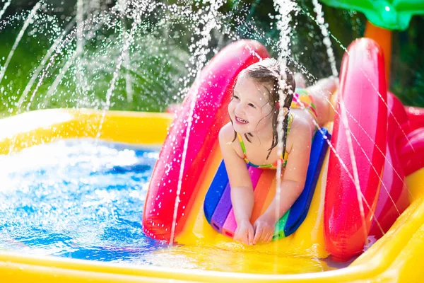 Menina que joga na piscina inflável do jardim — Fotografia de Stock