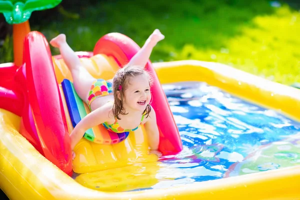 Маленькая девочка играет в надувной бассейн сад — стоковое фото