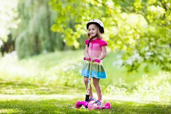 Lille pige ridning en farverig scooter - Stock-foto