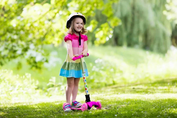 Küçük kız renkli bir scooter sürme — Stok fotoğraf