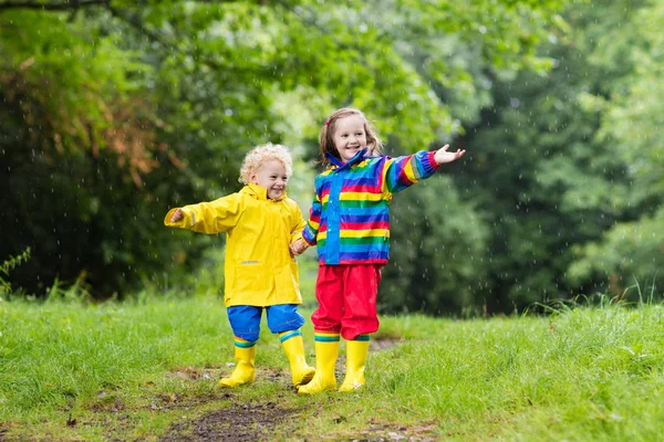 Los niños juegan bajo la lluvia y charco en otoño — Foto de Stock