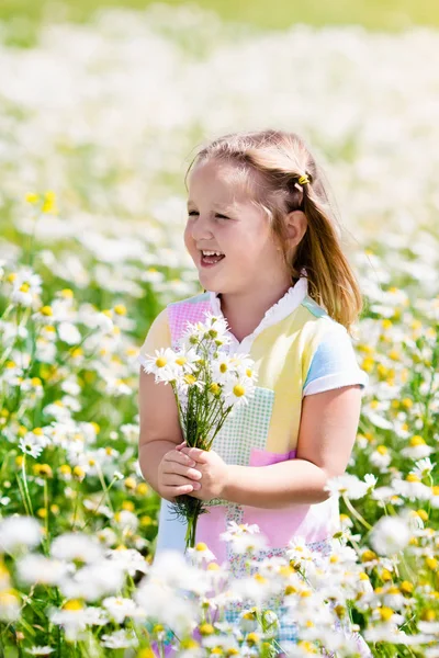 Little girl picking flowers in daisy field — Stock Photo, Image