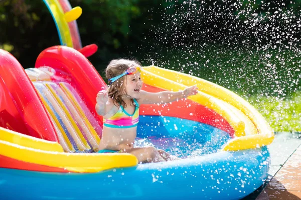 Criança na piscina do jardim com slide — Fotografia de Stock