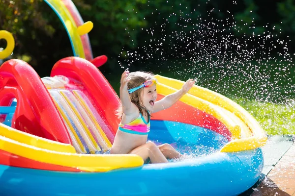 Criança na piscina do jardim com slide — Fotografia de Stock