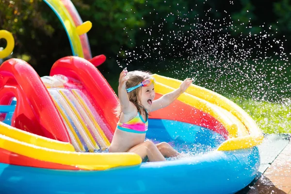 Child in garden swimming pool with slide — Stock Photo, Image