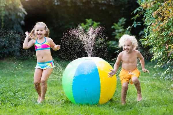 Bambini che giocano con spruzzatore giocattolo palla d'acqua — Foto Stock