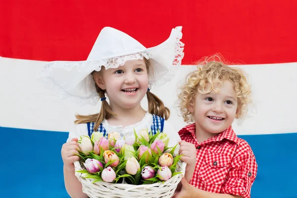 Dutch kids with tulip flowers and Netherlands flag — Stock Photo, Image