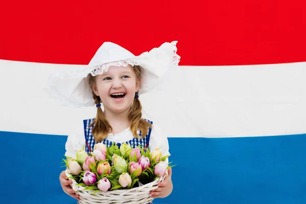 Голландский ребенок с цветами тюльпана и флагом Нидерландов — стоковое фото