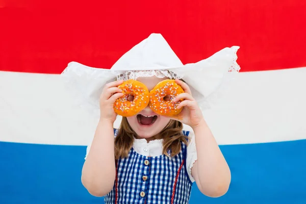 Holland lány narancssárga donuts és a holland lobogót — Stock Fotó