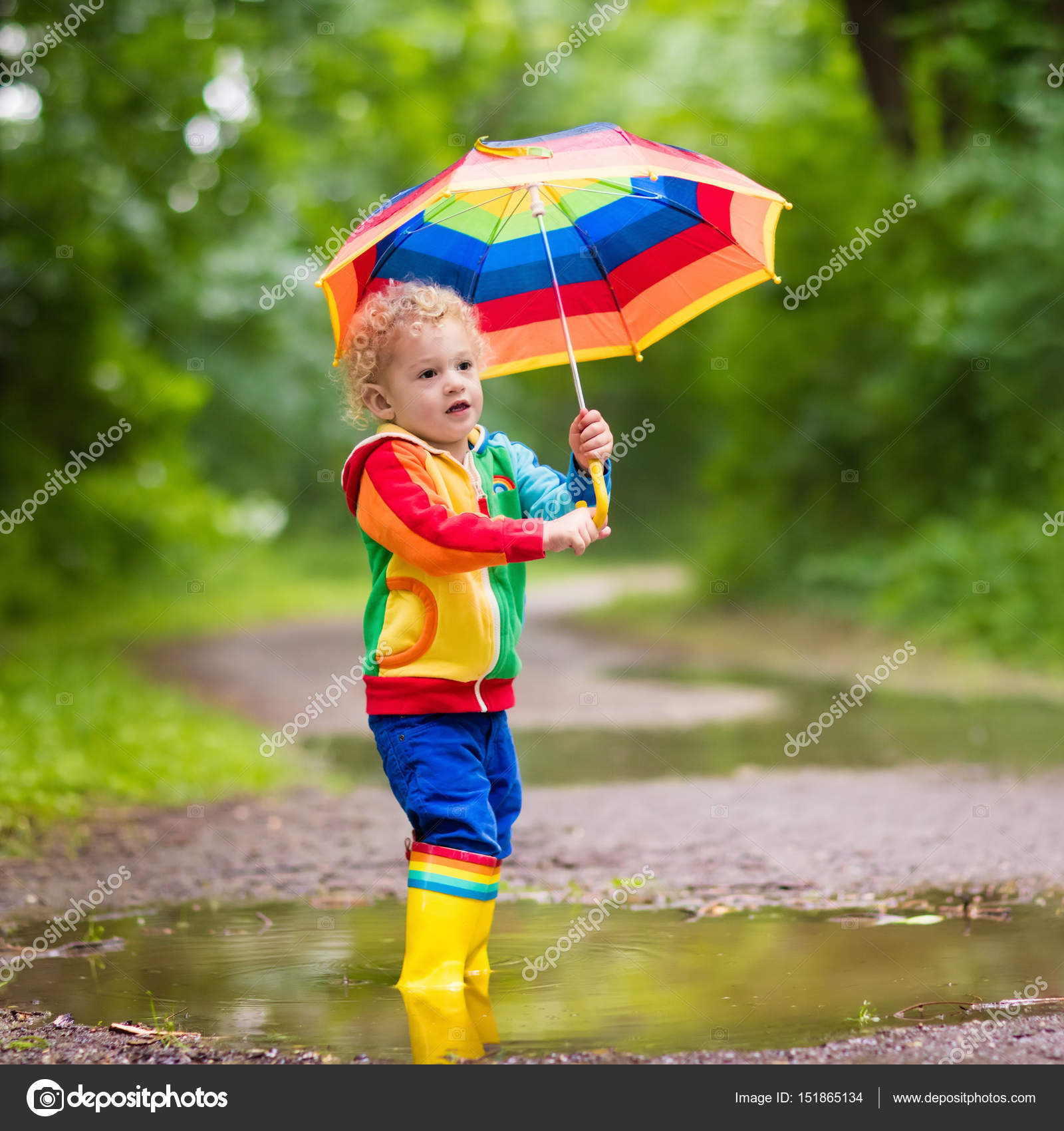 Child playing in the rain under umbrella Stock Photo by ©FamVeldman