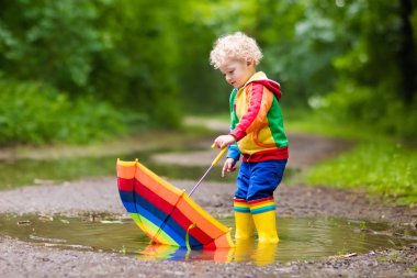 Yağmur şemsiyesi altında oynayan çocuk