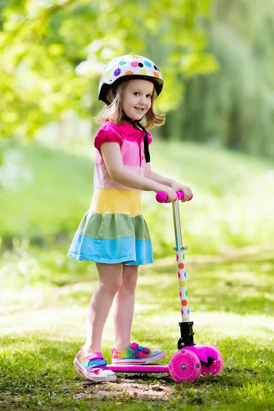 Mała dziewczynka jazda konna kolorowy skuter — Zdjęcie stockowe