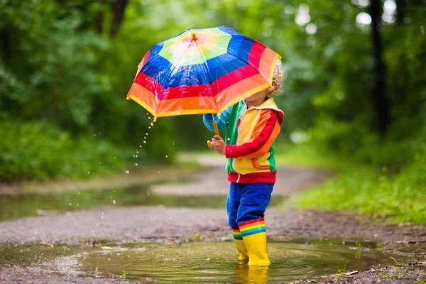 Criança brincando na chuva sob guarda-chuva — Fotografia de Stock