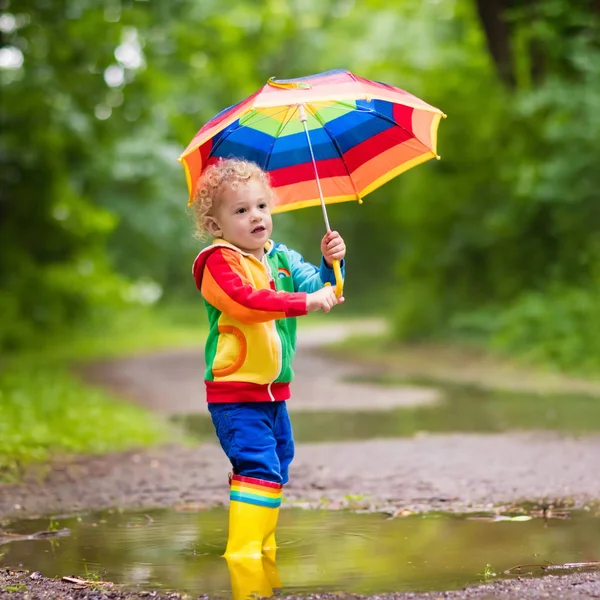 Criança brincando na chuva sob guarda-chuva — Fotografia de Stock