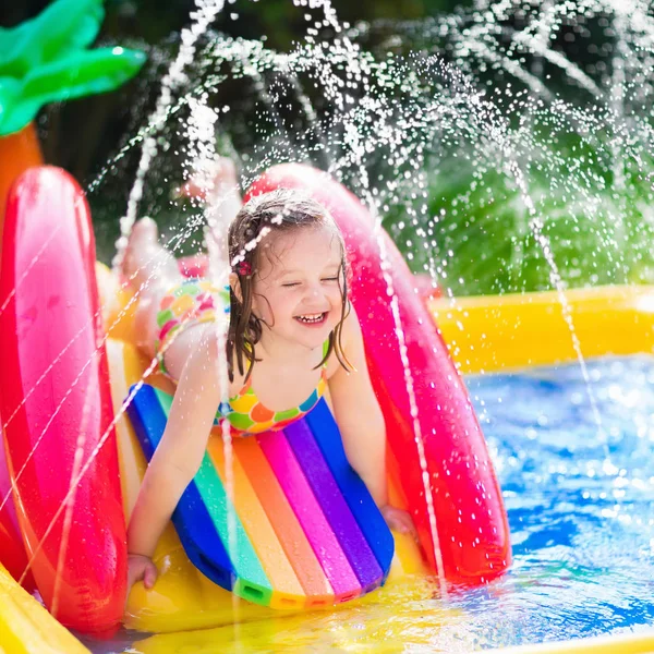 Menina que joga na piscina inflável do jardim — Fotografia de Stock