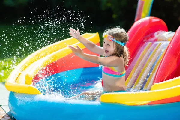 Child in garden swimming pool with slide