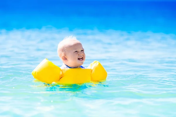 Baby swimming in ocean water on tropical beach — Stock Photo, Image