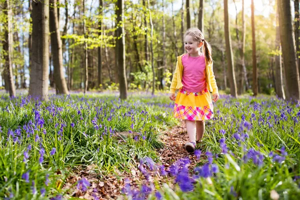 Ребенок с цветами колокольчика в весеннем лесу — стоковое фото