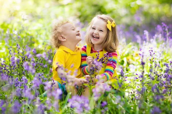 Kids playing in blooming garden with bluebell flowers — Stock Photo, Image