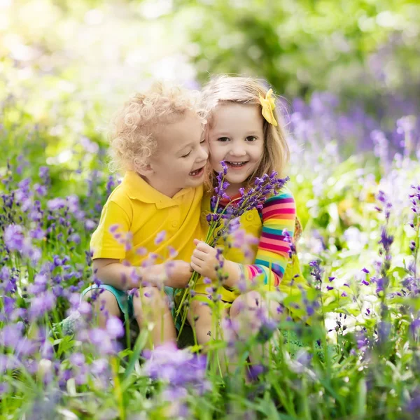 Niños jugando en el jardín floreciente con flores de Bluebell — Foto de Stock