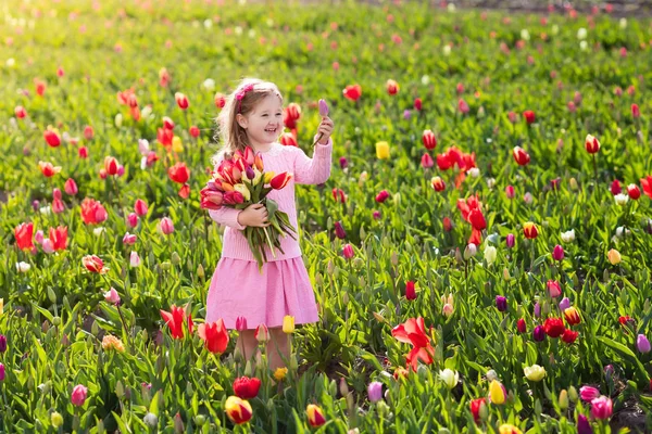 Klein meisje in tulip bloementuin — Stockfoto