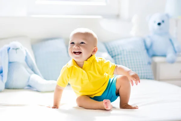 Baby pojke spelar på säng i soliga plantskola — Stockfoto