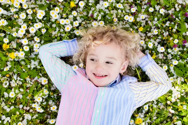 Ребенок на зеленой газоне с летними цветами — стоковое фото