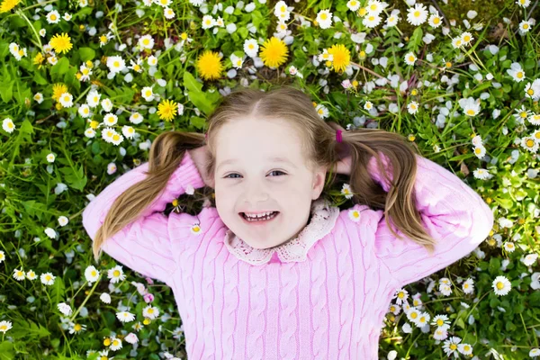 Criança no gramado de grama verde com flores de verão — Fotografia de Stock