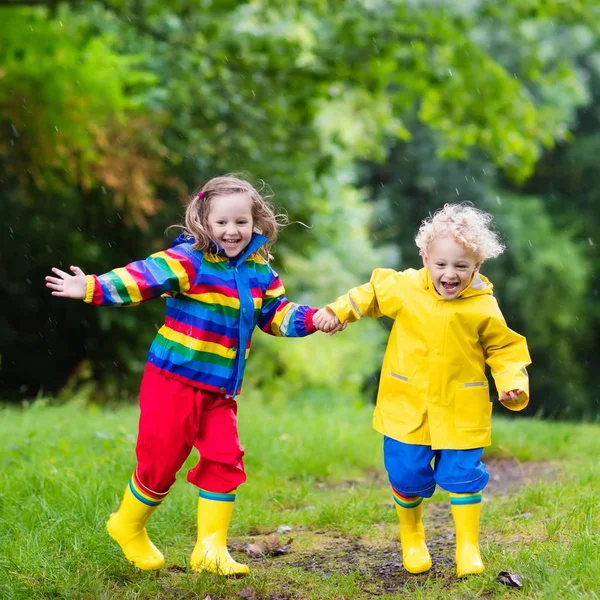 Kids play in rain and puddle in autumn — Stock Photo, Image