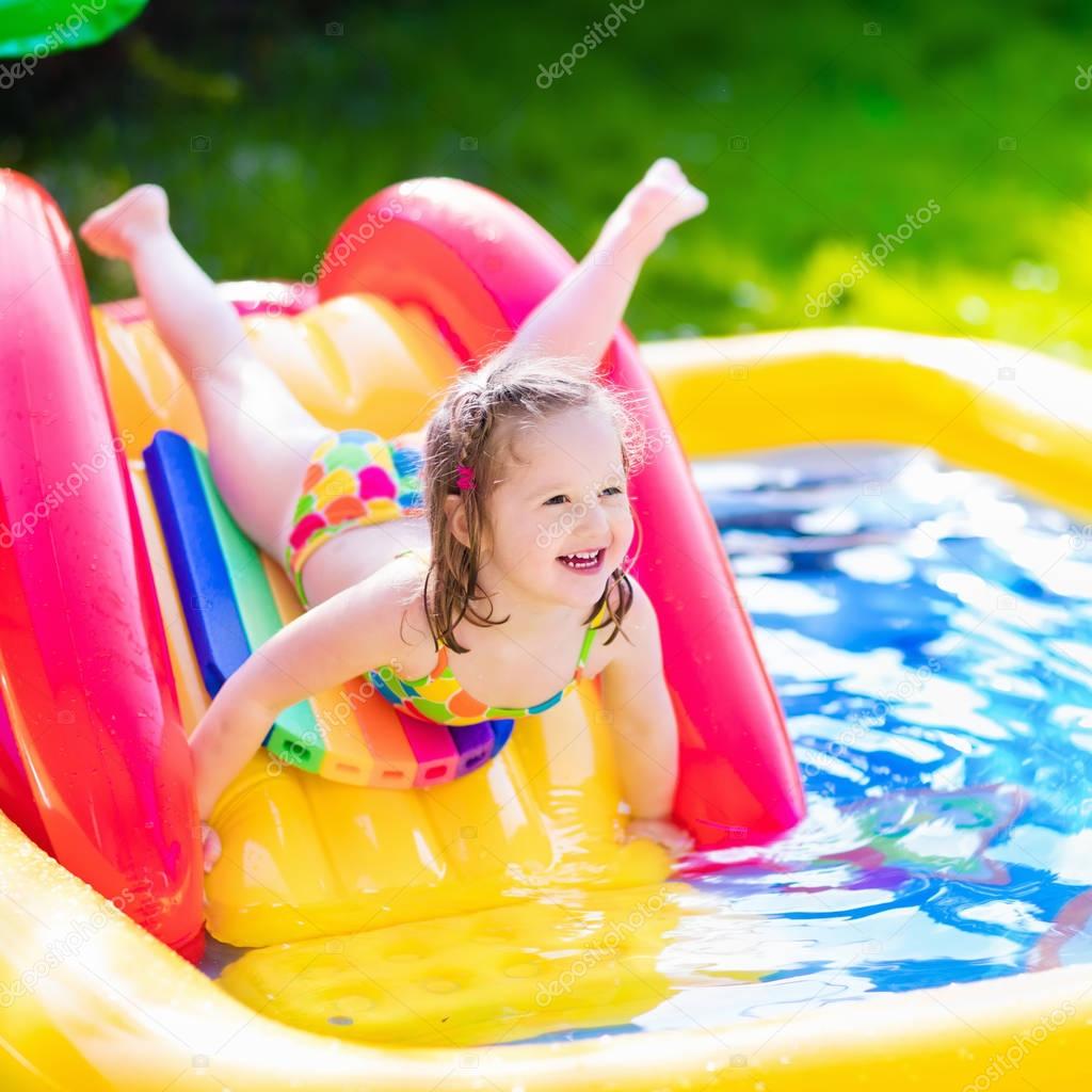 Little girl playing in inflatable garden swimming pool — Stock Photo