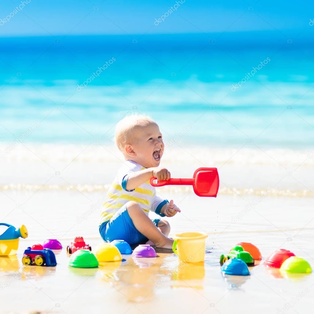 Baby playing on tropical beach digging in sand