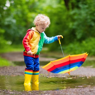 Yağmur şemsiyesi altında oynayan çocuk