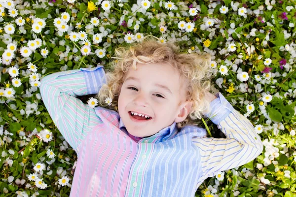 Kind auf grünem Rasen mit Sommerblumen — Stockfoto