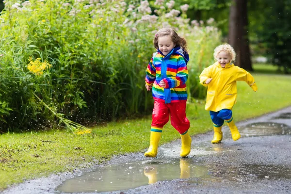 Los niños juegan bajo la lluvia y charco en otoño — Foto de Stock