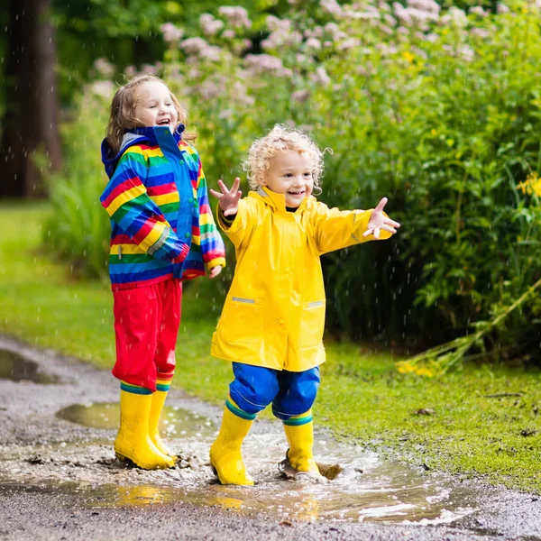 Kinderen spelen in de regen en plas in de herfst — Stockfoto