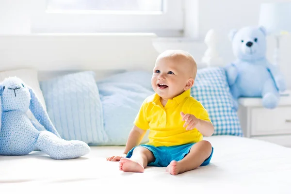 Baby boy playing on bed in sunny nursery — Stock Photo, Image