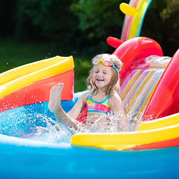 Child in garden swimming pool with slide