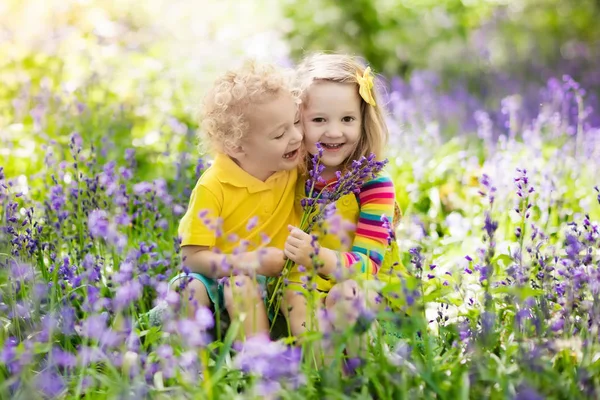 Kinder spielen im blühenden Garten mit Blauglockenblumen — Stockfoto