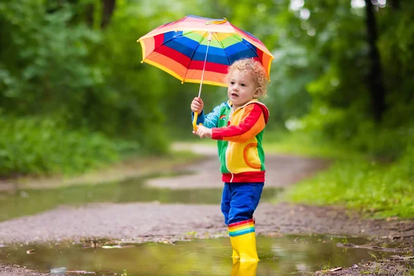 Child playing in the rain under umbrella Stock Photo