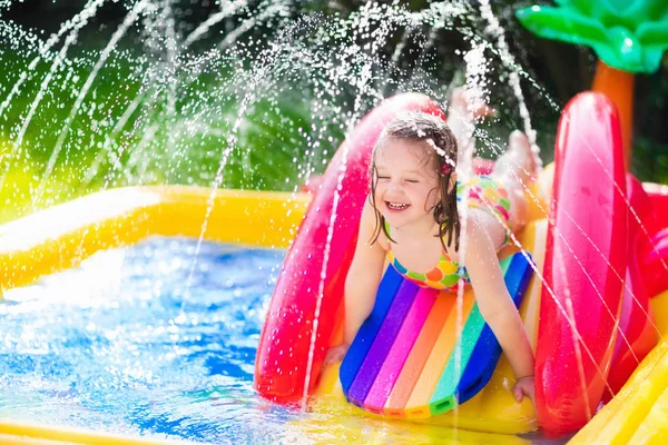 Menina que joga na piscina inflável do jardim — Fotografia de Stock